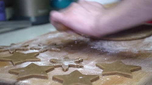 Caucasian female working on gingerbread dough with a rolling pin.