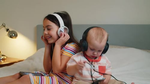 Children Listening to Music with Headphones on Bed