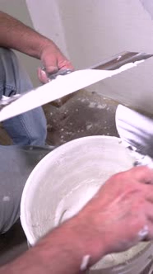 Close-up of Hand Mixing White Joint Compound in a Bucket