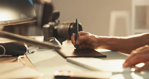 Hands Use Stylus on Tablet in Creative Workplace