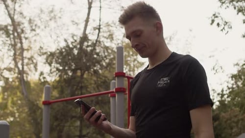 Man Using Phone After Workout in Urban Park