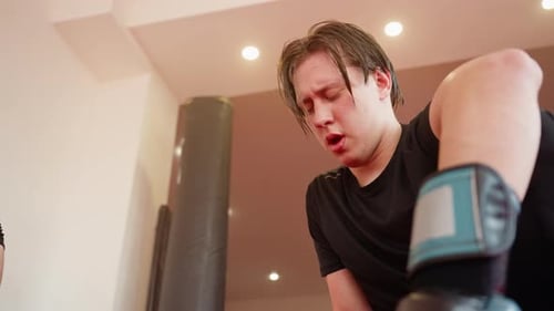 Male Fighter Resting After Sparring in Gym Wearing Black Sportswear