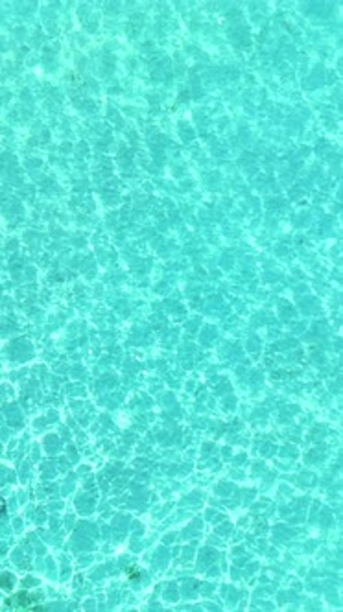 Top View of Tropical Beach with White Sand and Clear Blue Ocean Turquoise Water in Natural Sunlight
