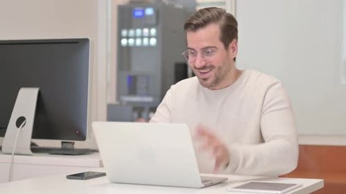 Excited Young Man Celebrating Success on Laptop in Office