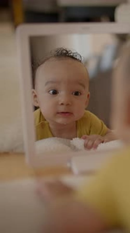 Cute Infant Gazes at Reflection in Mirror