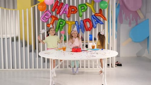 Girls celebrating happy birthday with cake and balloons
