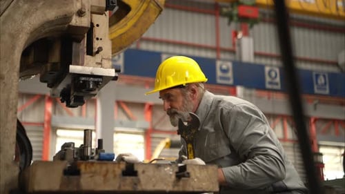 Senior experienced technician checking and maintenance a large machine in metal sheet factory