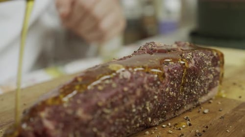 Preparing Seasoned Steak with Oil on Cutting Board