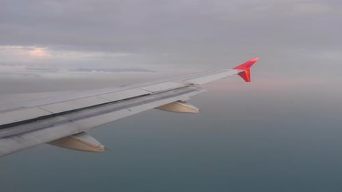Airplane Wing Soaring Above Ocean at Golden Hour