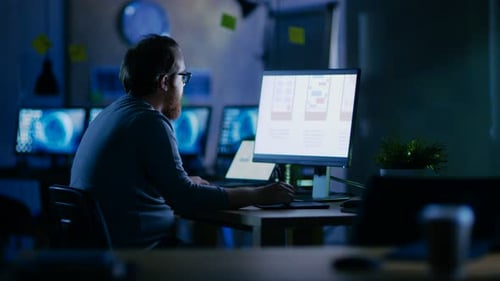 Male Mobile Application Developer Works with Graphics on His Personal Computer with Two Monitors. H