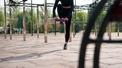 Woman Exercising with Resistance Band at Outdoor Gym