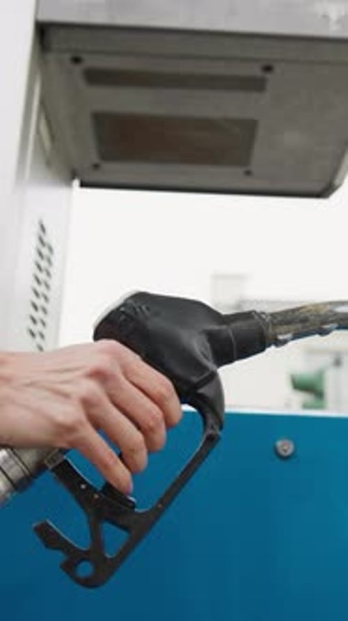Hand Presses Fuel Gun at Gas Station