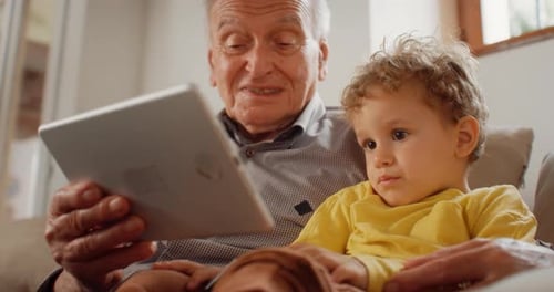 Senior Man and Toddler Using Tablet Indoors