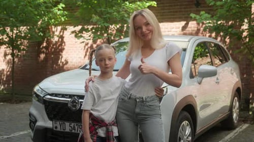 Smiling Woman and Child Giving Thumbs Up by Car