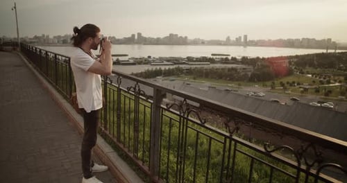 Man Photographs Cityscape at Golden Hour
