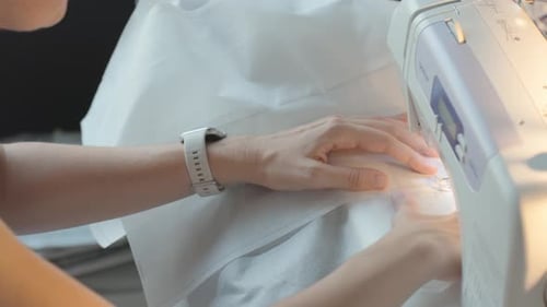 Person, die zu Hause Stoff auf einer elektrischen Nähmaschine näht