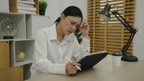 stressed woman using a digital tablet at home office