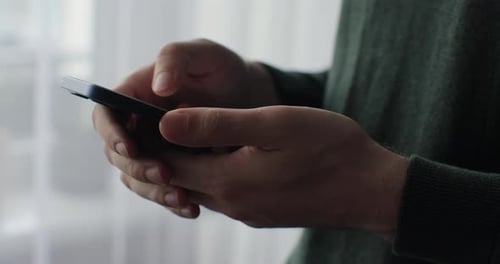 Close Up Young Man Holding Mobile Phone in Hands Texting Message in Web Chat Surfing Reading News