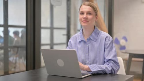 Smiling Woman Working on Laptop in Office