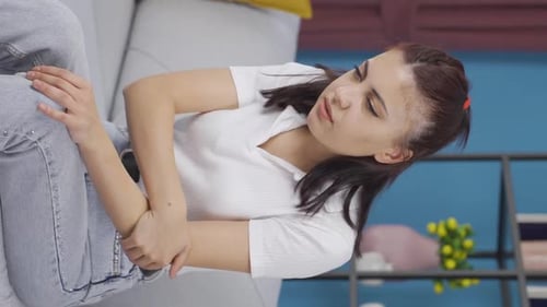 Woman Lying on Couch Holding Her Arm