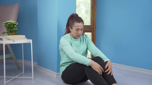 Sad Woman Sitting on Floor in Blue Room
