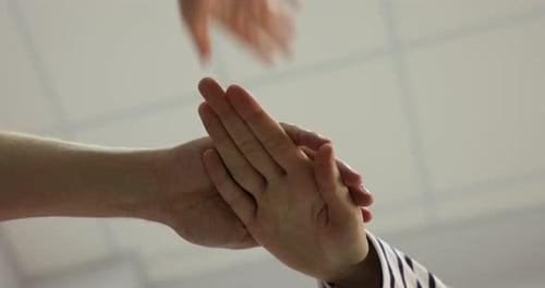 People holding hands together indoors, bottom view. Team building