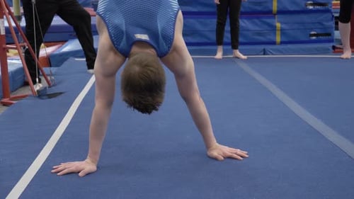 Junge, der beim Gymnasium auf Händen läuft, Leistung