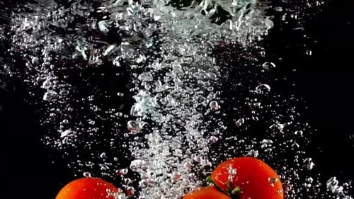 Tomatoes Splashing into Water on Black Background