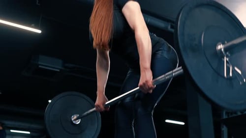 portrait of a concentrated fitness woman doing a heavy shoulder press exercise with a barbell in gym