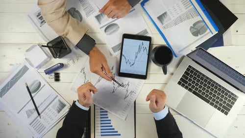 Top View Male Hands of Two Young Businessmen Checking Graphs and Discussing Financial Reports in