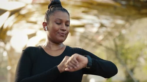 Woman Athlete After Exercising Checking the Pulse on the Smart Watch in Her Hand After the Run