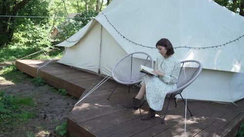 Woman Reading a Book at Glamping Tent