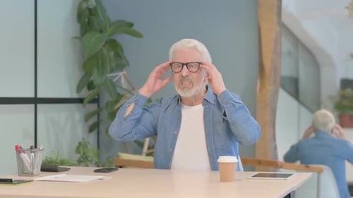 Man Massaging Temples and Rubbing Neck Indoors