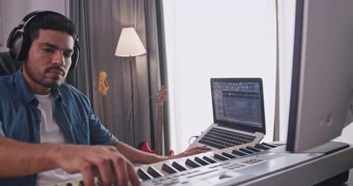 A musician is creating new music in his home studio.