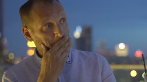 Sad, Unhappy Man Drinking Cocktail Sitting on Terrace in Bar at Night Alcohol