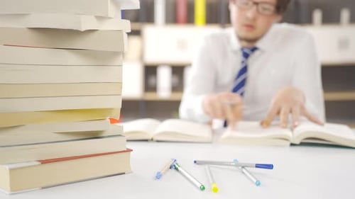 Student, der zwischen einem Stapel Bücher studiert.