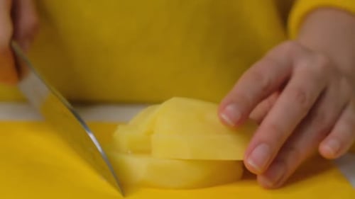 Hands Dicing a Potato into Cubes on Board