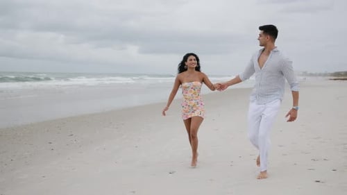 Romantic Couple Running Hand in Hand on a Beach