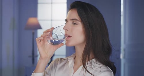 Woman Drinks Water in Interior Setting