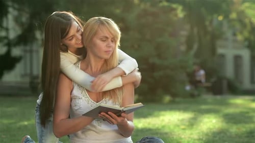 Woman Reading as Girl Hugs her Shoulders