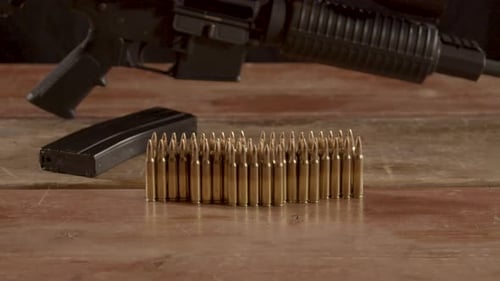 Wide dolly out of 5.56mm ammo standing on a wooden surface with an AR-15 in the background