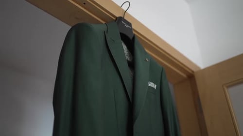 Close up of a green suit jacket hanging on a hanger in a doorway, viewed from below.