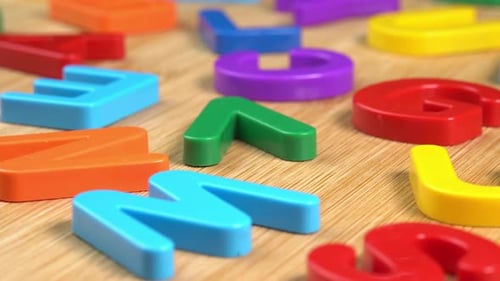Colorful letters rotate on a wooden background. The concept of learning, school or college