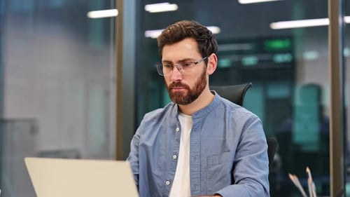 Focused Businessman Working on Laptop in Modern Office