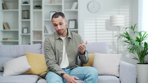 Man Sitting on Couch Feeling Hot Indoors