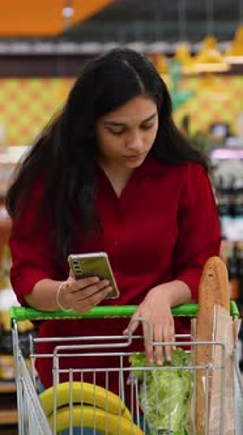 Focused Woman Using Smartphone in a Supermarket