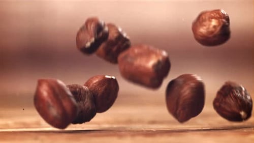 Hazelnuts Falling onto a Wooden Surface Close Up