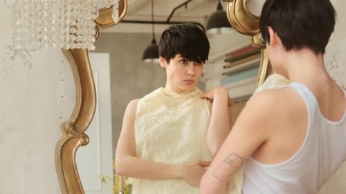 Uma jovem escolhe roupas na frente de um espelho, o que vestir. Preparando-se