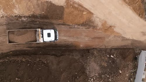 Bucket loader loading soil onto a truck trailer, Top down view
