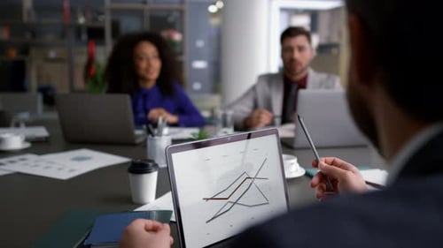 Business Meeting with Colleagues Discussing Chart on Laptop
